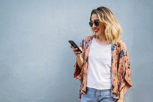Blonde woman with beachy waves looking at her phone